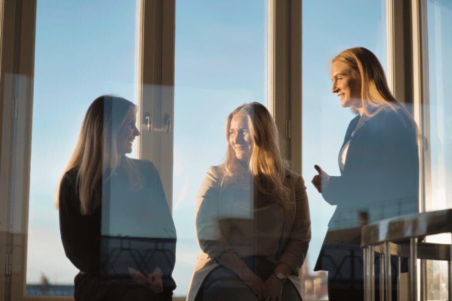 3 kvinnor som samtalar framför ett fönster