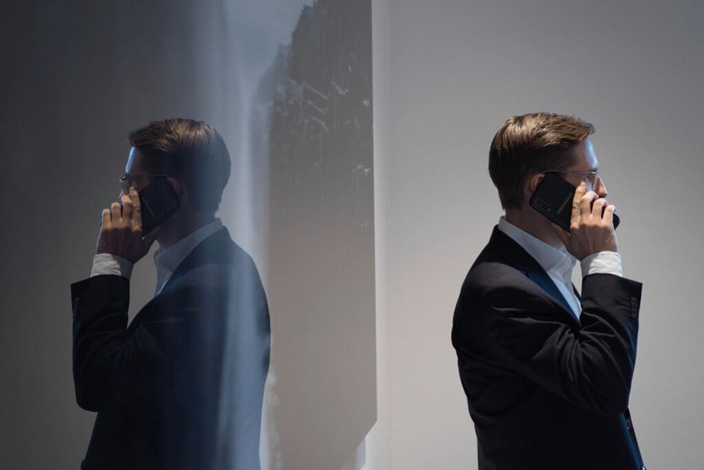 En man i profil som pratar i telefon framför en stor tavla